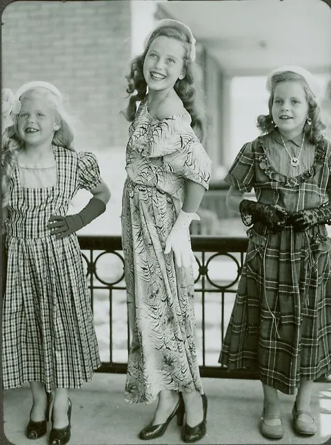My mom (middle) and aunts playing dress up on the porch, 1950s