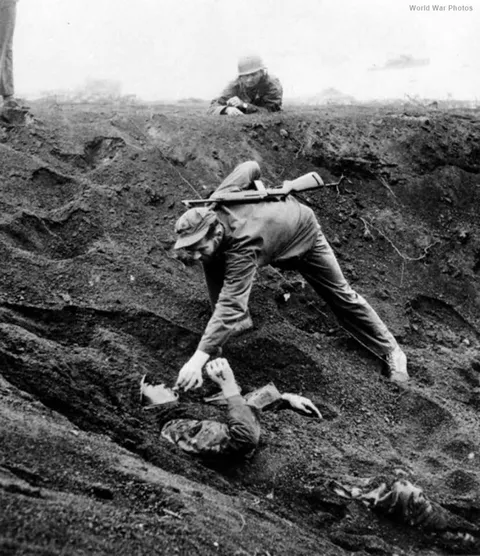 Marine approaches a Japanese soldier on Iwo Jima, March 16, 1945. The soldier had been buried for 36 hours in a shell hole, pretending to be dead, with a live grenade just inches from his hand.