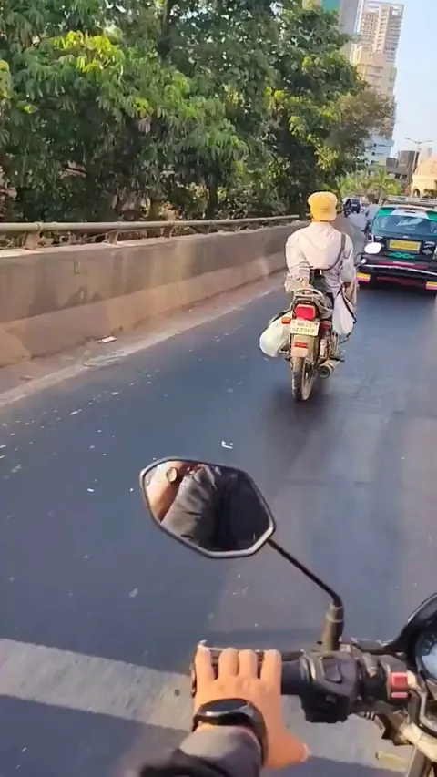 Guy casually riding a bike with no hands in traffic like it’s nothing
