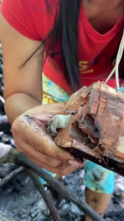 Woman in the woods sucks up some kind of worm from a log