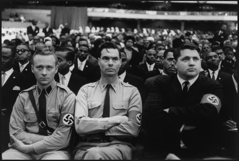 George Lincoln Rockwell, flanked by his henchmen, listening to Malcolm X's speech by Eve Arnold 1962
