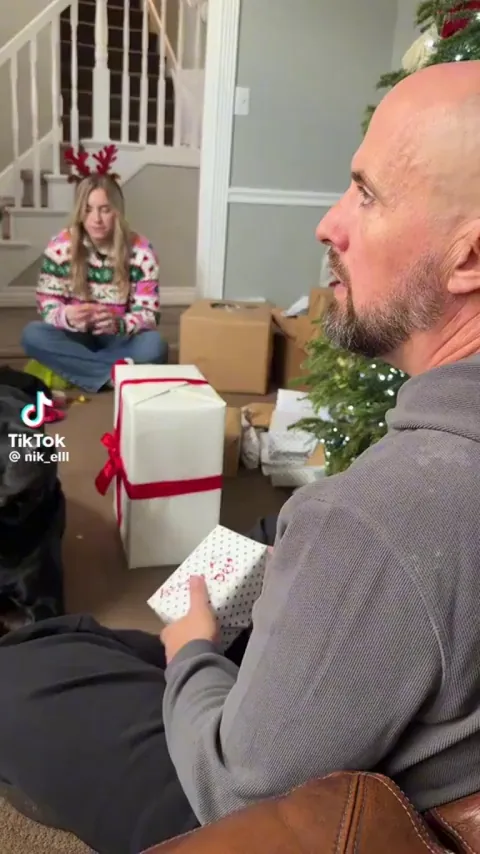 Their dog opening his Christmas present.