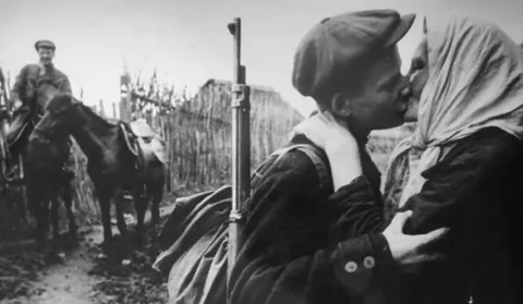 A mother gives her son one last kiss before he leaves to become a Soviet partisan