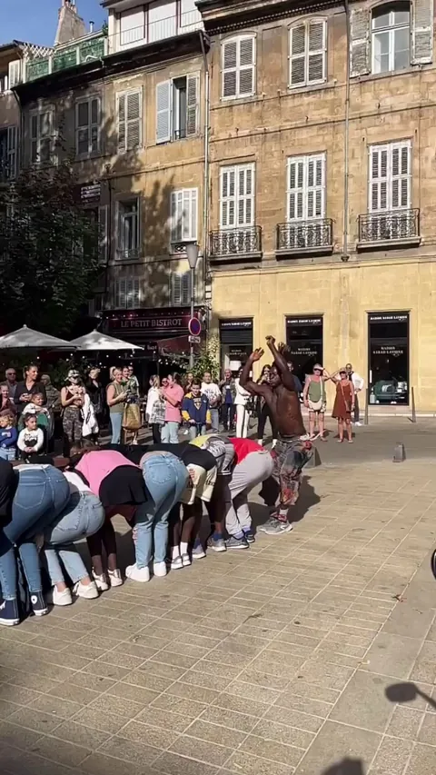 A dude does a frontflip over nine people who are bent over