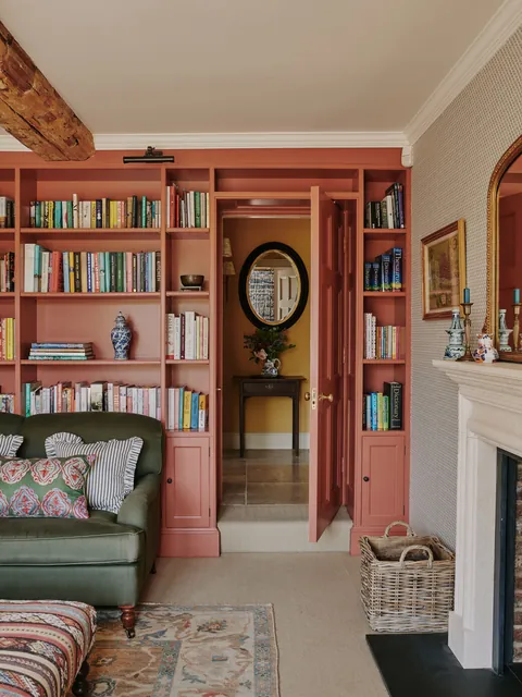 TV room lined with soft red bookshelves in a renovated former Georgian rectory, Hampshire, England [2000x2667]