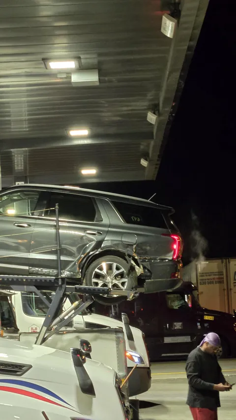 This SUV on top of an auto carrier is running.