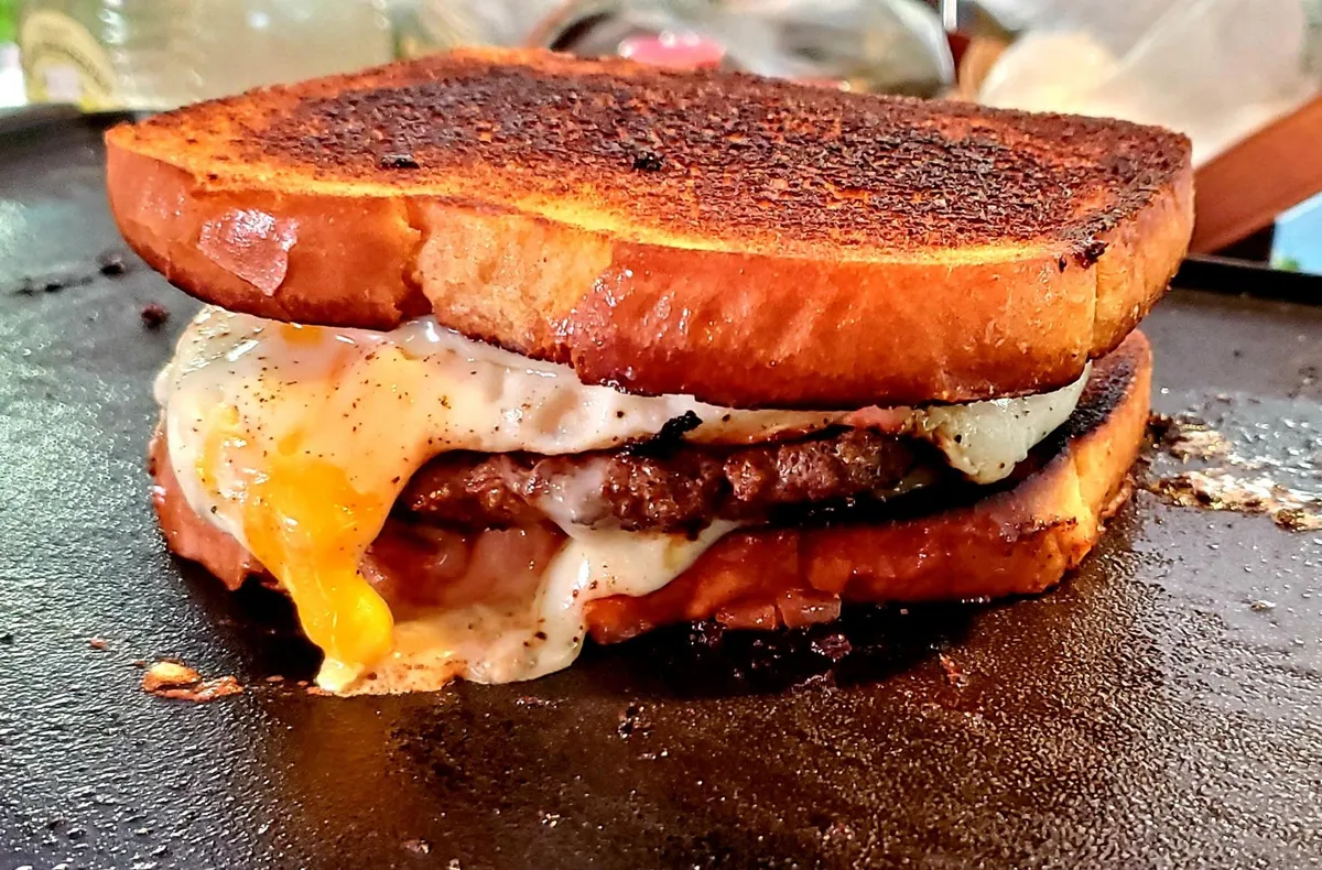 Patty melt with fried egg and white American cheese on potato bread.