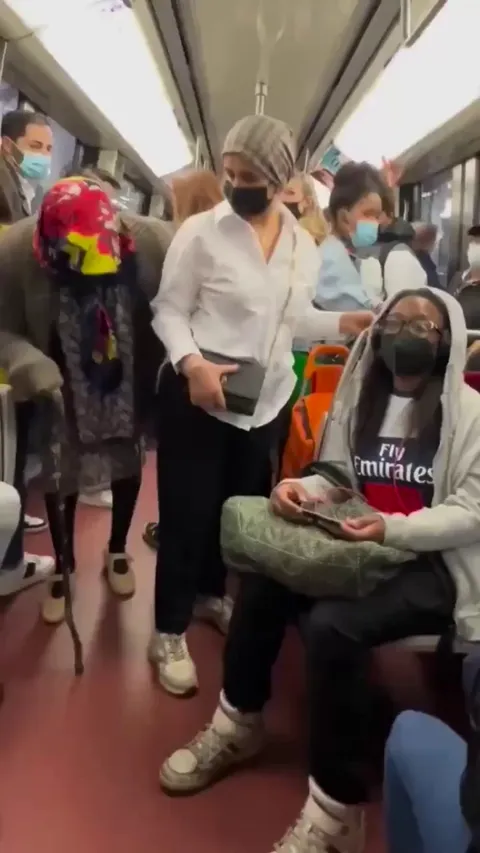 A woman offers her seat to a senior.