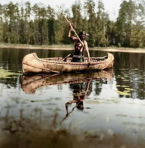 A 1908 photo of an Ojibwe Native American in a birchbark canoe