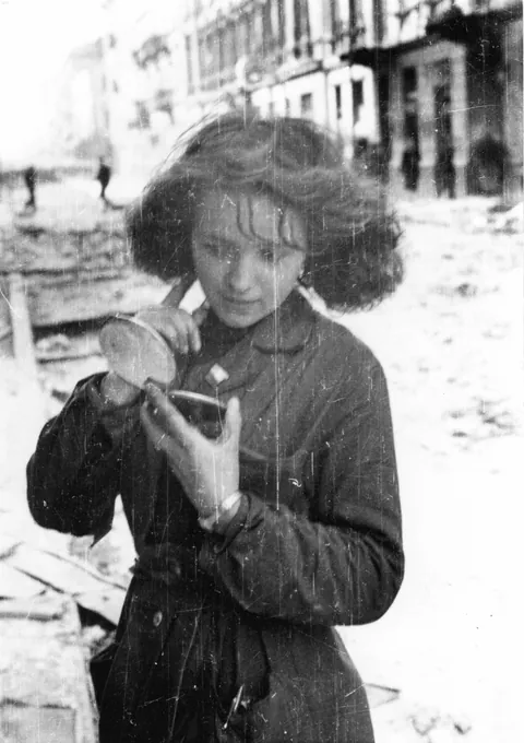 A Polish resistance fighter checks her hair after a German air raid during the Warsaw Uprising, September 1944