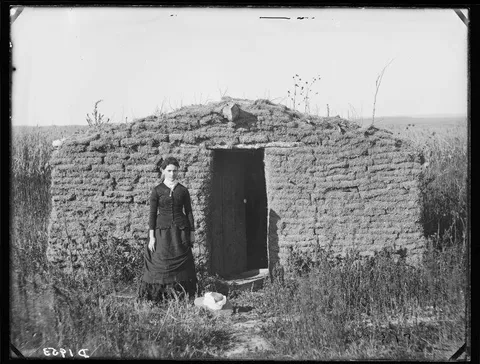 Female homesteader Mary Longfellow poses next to her sod house in Broken Bow, Nebraska. Photo circa 1880s.