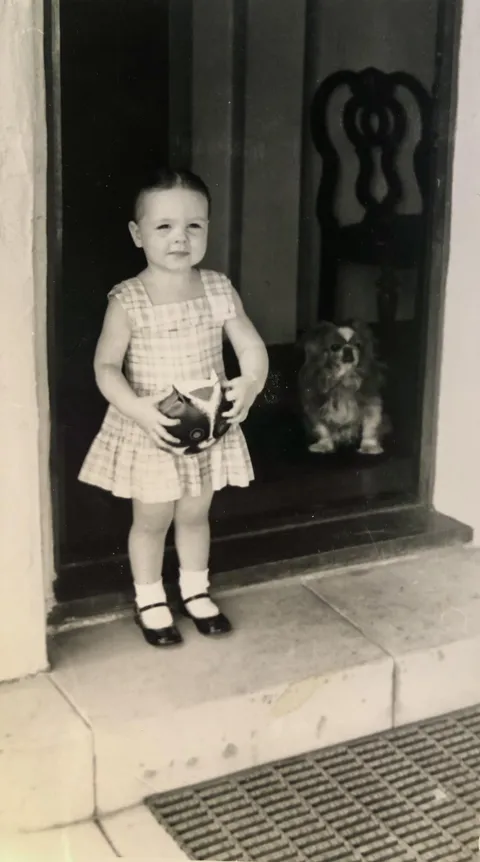 Visiting my grandmother with my cat purse in hand, 1957