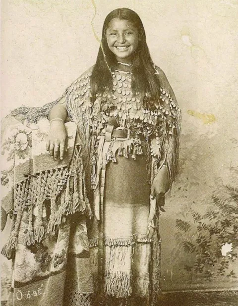 This rare photograph shows a young indigenous woman smiling at the viewer. The image was taken at George W. Bretz’s studio in Fort Sill, Oklahoma(1894)