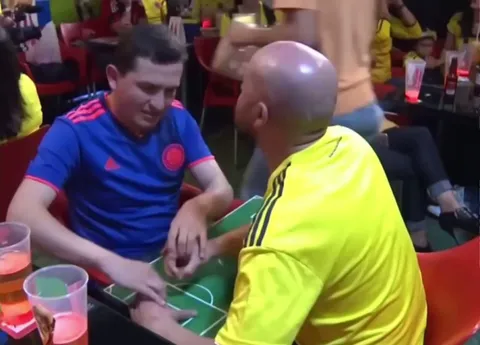 A person helps a blind man follow the game through his fingers, watching Colombia vs Poland in Group H 2018 