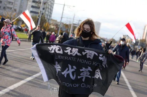 Belarus protester holding up the flag of Hong Kong democracy protest: "Liberate Hong Kong. Revolution of Our Times"