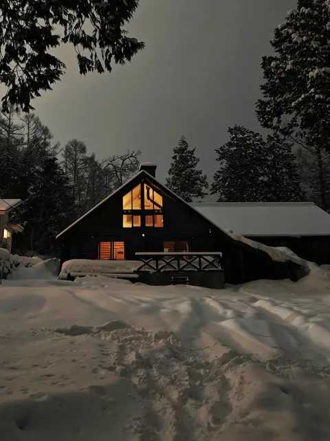 The warm glow of cabin lights on a cozy snowy night