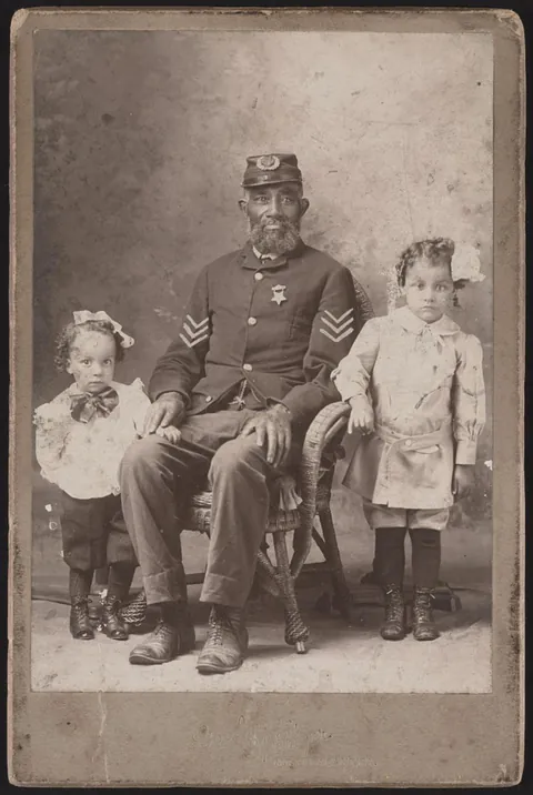 Civil war veteran poses with his grandchildren, circa 1880. Cabinet card