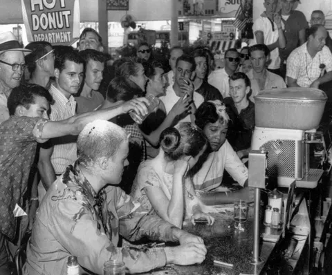 Ketchup, mustard, and sugar being poured on the heads of college students at a sit-in protest in a Jackson, MS Woolworth's store 1963.