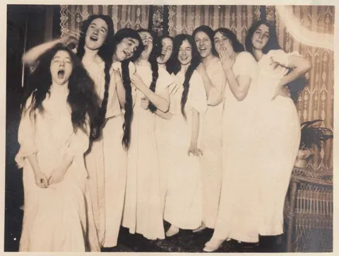 Teenage girls at a slumber party, yawning for the camera, circa 1910.