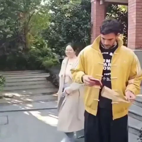 Person in a yellow coat is thrilled to get a gift of Mao's Little Red Book in China (75 *million* dead civilians)