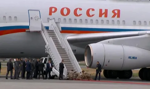 US Soldiers kneeling to roll out the red carpet for Putin while Russian bodyguards stand and watch.