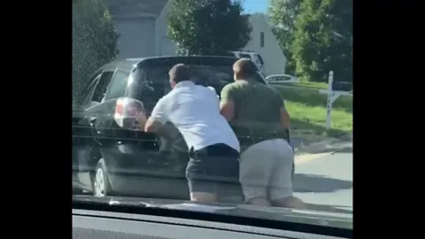 Golden retriever getting out of stalled truck to help push it up the driveway