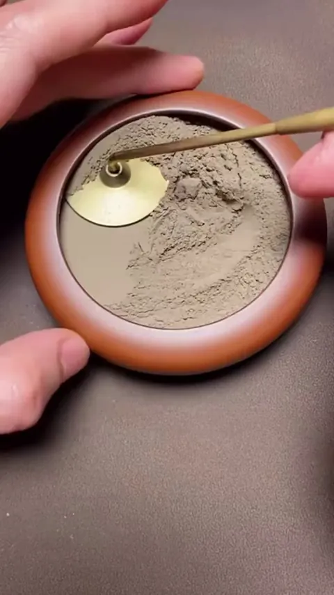 Leveling out a small pot of sand and adding incense