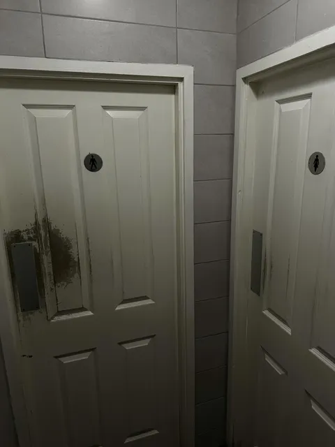 The difference in wear on the toilet doors in the pool club.