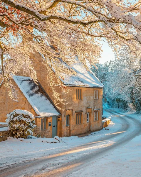 Stone cottage in the Cotswolds village of Saintbury covered in snow, Gloucestershire, England.