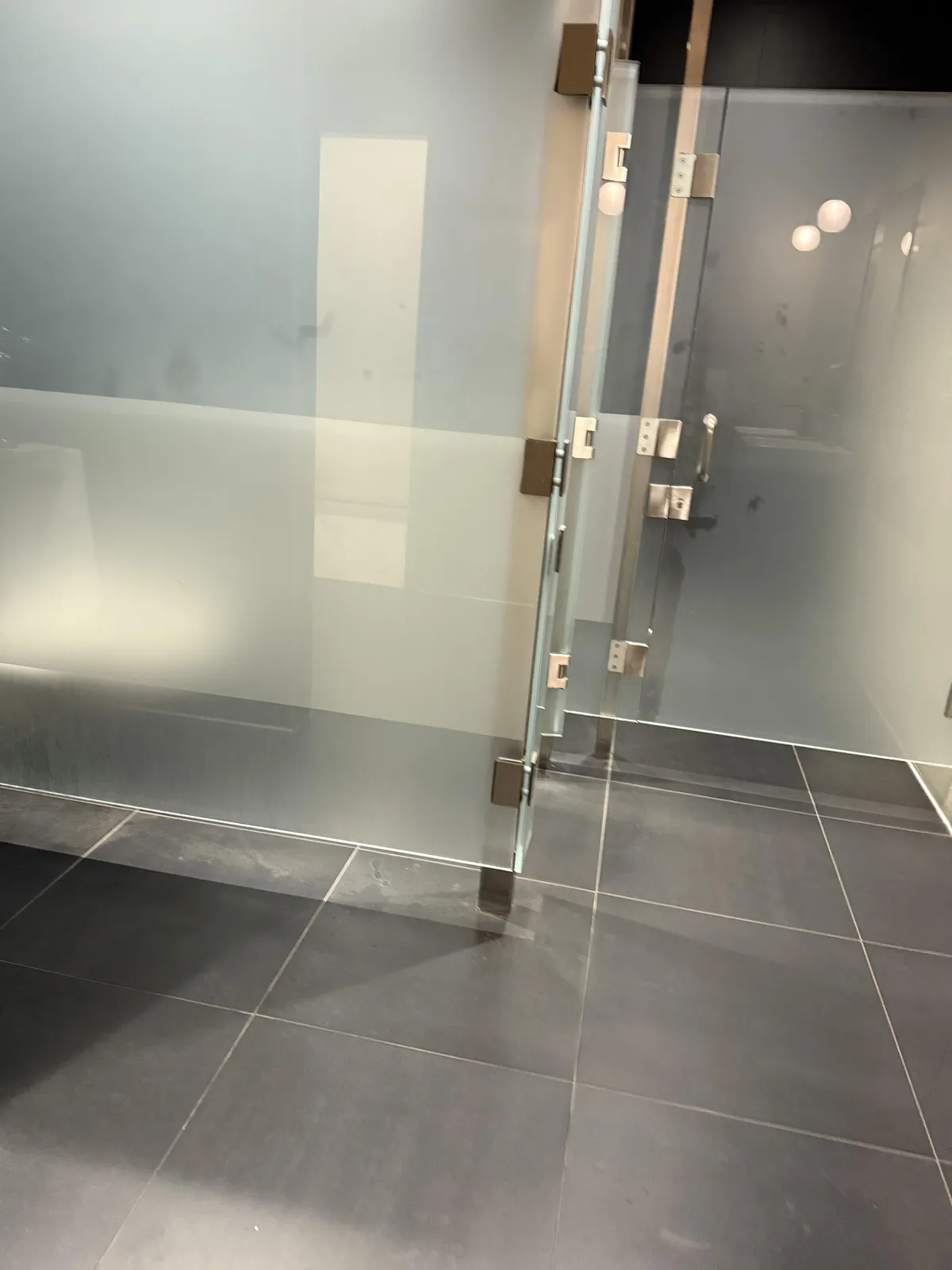 The men’s restroom at a car dealership has almost clear toilet stalls