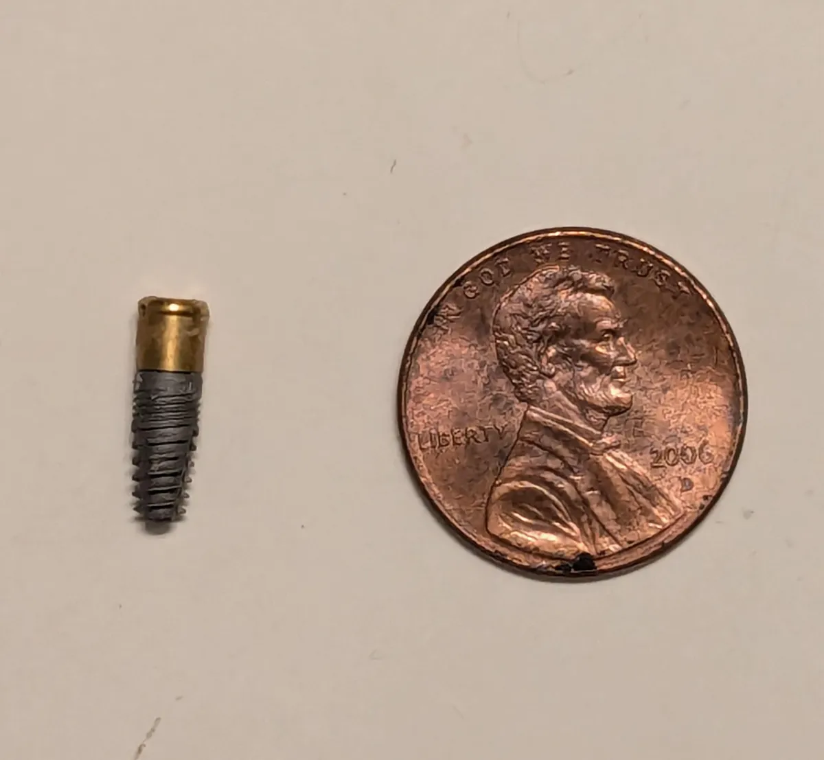 The dental implant I accidentally pulled out of my jaw. Penny for scale.