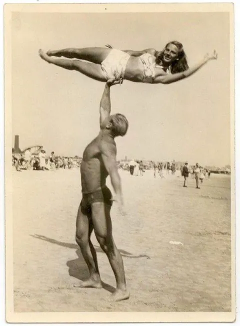 Man at Muscle beach, California, has fun with a woman (maybe girlfriend?) by doing a one arm hold by the hip, 1940s