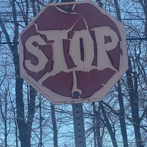 A stop sign in my town is so old it's become a death metal band logo