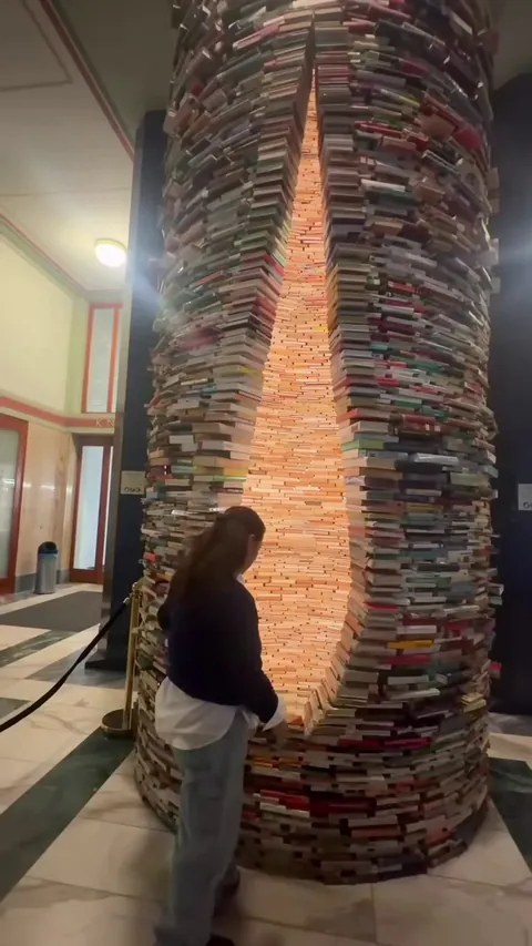 ​The Infinity Book Tower in Prague titled Idiom. Over 8,000 books stacked securely into a column with a teardrop-shaped viewing opening.
