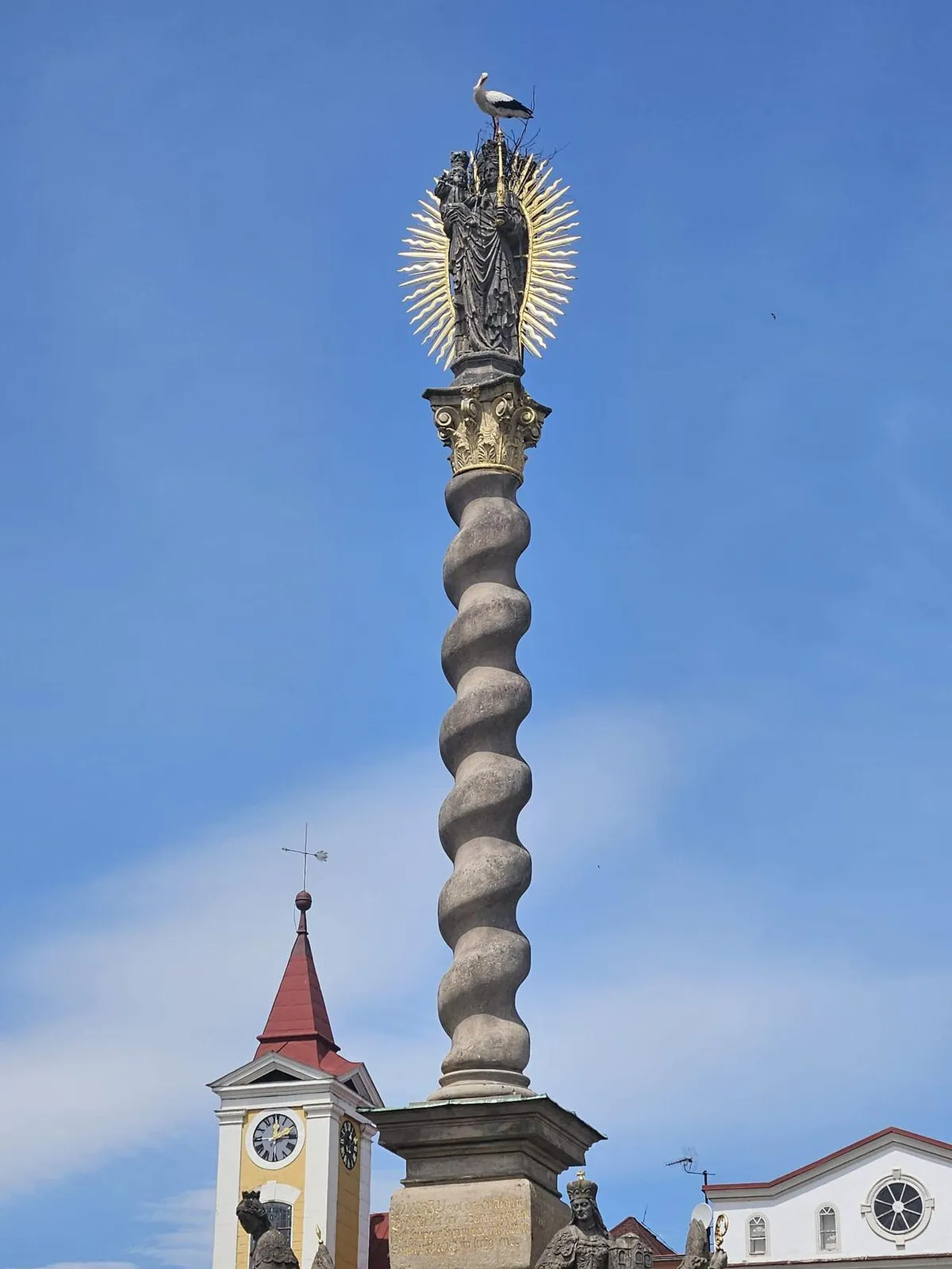 A stork has started building a nest on the plague column in Broumov, Czech Republic.