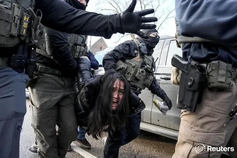 Federal agents grab a woman to drag her away from her car, Minneapolis, Minnesota, January 13, 2026.
