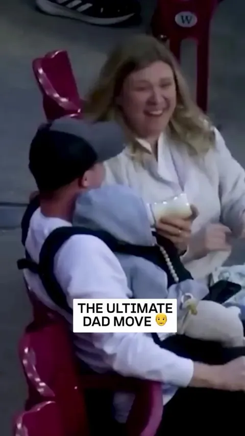 Dad catches a ball with one hand while feeding the baby