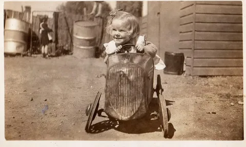 My mum making her getaway in a tin peddle car, 1948