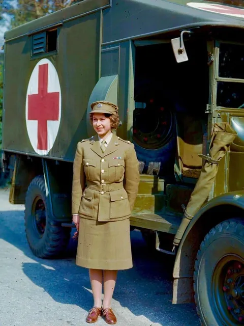 The Future Queen Elizabeth II of England, 1926-2022, a 2nd subaltern in the Women’s Auxiliary Territorial Service (ATS) stands by an ambulance in April 1945. Decades later, The Queen is photographed gazing at a mannequin wearing a uniform similar to what she wore years prior.