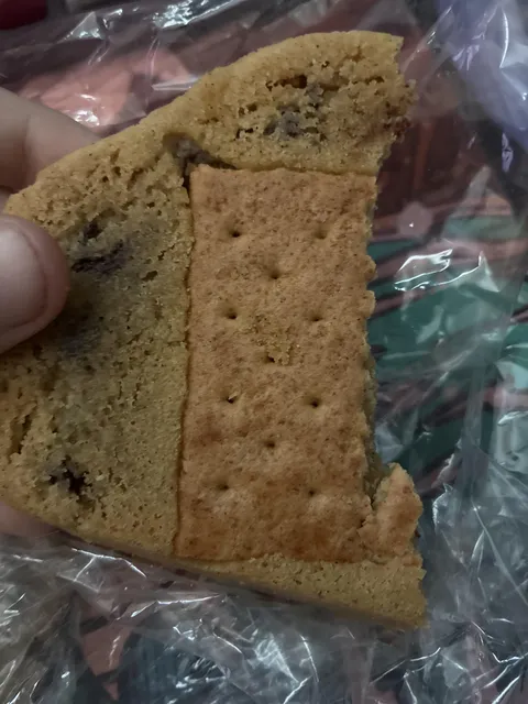 A cookie from a local cookie shop had a random graham cracker slotted into the bottom of it.