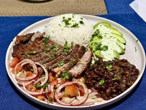 Carne asada with rice, beans, avocado, tomatoes and onions in balsamic vinegar, and garlic cilantro sauce.