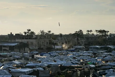 Israeli bomb mid-air as it falls toward a densely packed tent camp for displaced Palestinians
