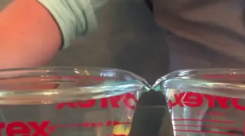 When a high voltage is applied to pure water filling 2 beakers kept close to each other, a connection forms spontaneously, giving the impression of a floating water bridge