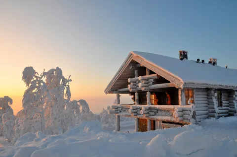 Typical finnish cabin covered with snow. This shot was made in Lapland - a unique place where the sunrise is at the same time the sunset.