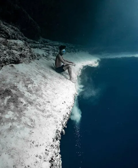 The terrifying beauty of the ocean. A man sitting on the edge of an underwater cliff.