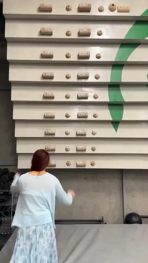 Woman climbing wall with arms only