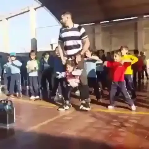 Compassionate gym teacher helps a little girl dance with her classmates