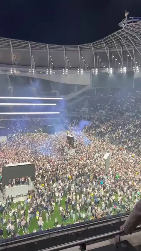 Fans celebrating on the pitch and climbing the big screens at the Tottenham Hotspur Stadium