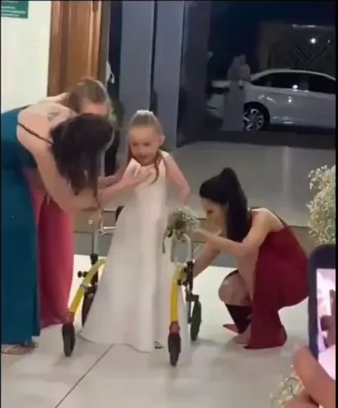 DESPITE HAVING CEREBRAL PALSY, THIS LITTLE GIRL WALKS DOWN THE AISLE AS THE RING BEARER FOR HER PARENTS WEDDING.