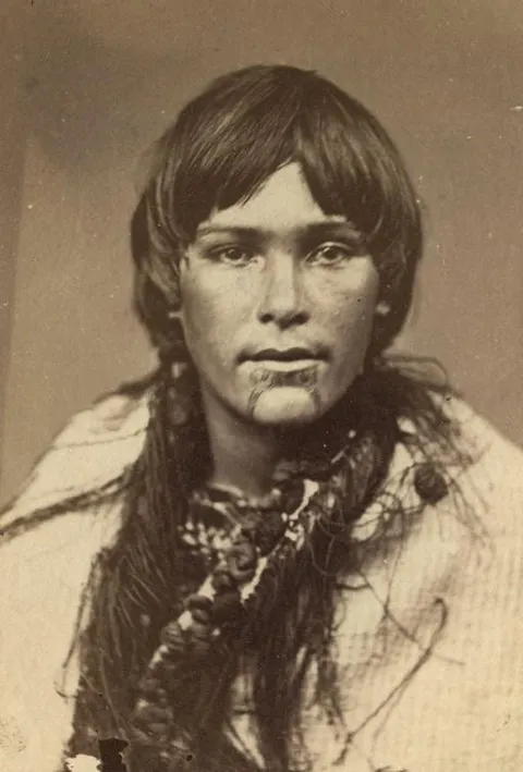 A young Māori woman with traditional tattoos (moko) on the lips and chin (c. 1860–1879)